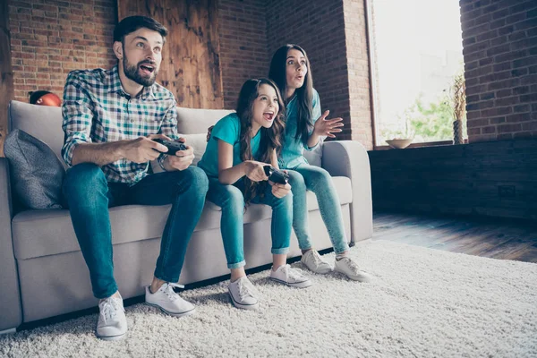 Retrato de personas emocionadas sentadas diván usando vaqueros camisa a cuadros jugando carrera en casa en el interior — Foto de Stock