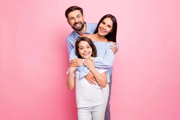 ピンクの背景に隔離されたチェック柄のチェック柄のシャツオフショルダー白いTシャツを着て笑顔を抱く陽気な家族の肖像画 — ストック写真