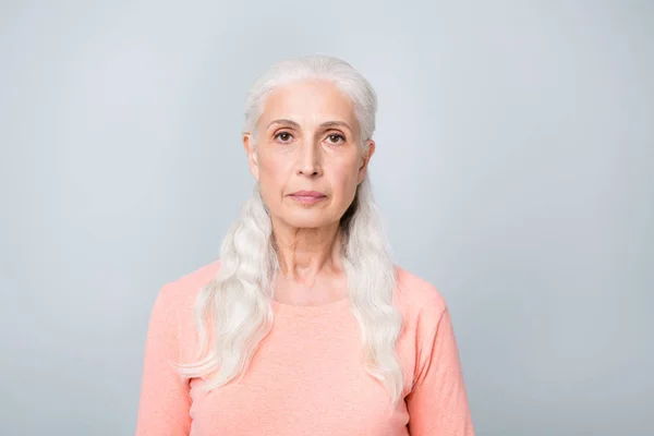 シンプルな桃色のプルオーバーを着て真剣に焦点を当てた魅力的な老婦人のクローズアップ写真孤立した灰色の背景 — ストック写真