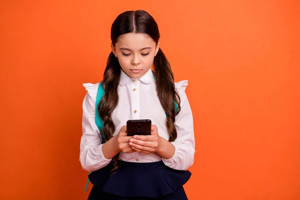 Retrato de niño lindo enfocado cogido de la mano cursos de tecnología moderna en el aula blogger usuario de las redes sociales usar blusa blanca moderna falda vestido bolso mochila mochila aislado fondo naranja —  Fotos de Stock