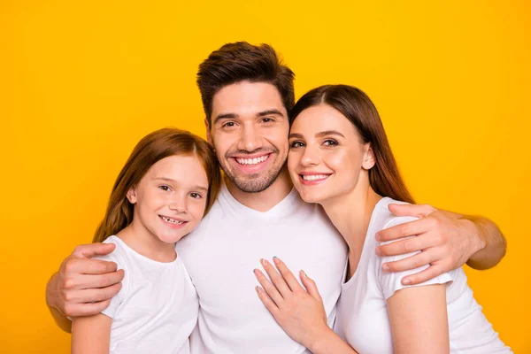 一緒に幸せに抱きしめる3人の家族のクローズアップ写真は、カジュアルな衣装孤立した黄色の背景を着用 — ストック写真