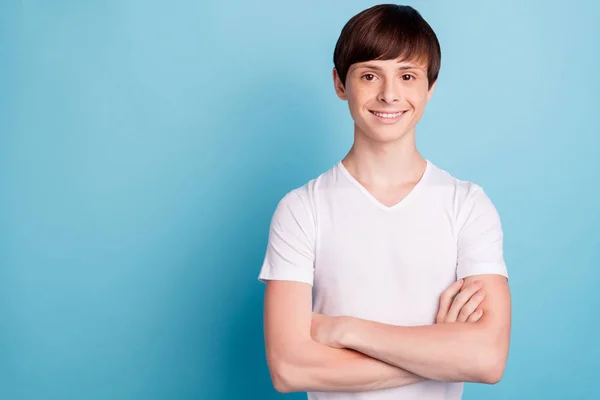 Foto von attraktiven fröhlichen netten Jungen, der mit verschränkten Armen vor der Kamera steht, während er isoliert vor blauem Hintergrund steht — Stockfoto