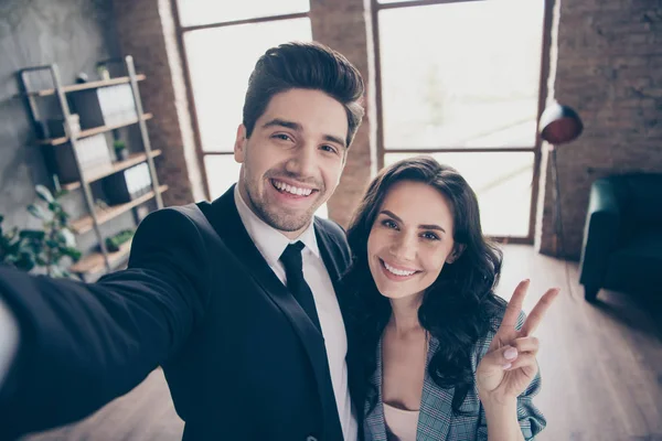 Foto de dos socios haciendo selfies en la nueva oficina del taller mostrando trajes de vestir formales con signo v — Foto de Stock