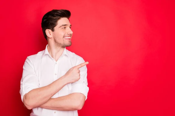 Retrato de su agradable atractivo alegre contenido alegre empleado apuntando dedo índice a un lado anuncios consejos de publicidad venta de retroalimentación solución de descuento aislado sobre brillante brillo brillante fondo rojo — Foto de Stock