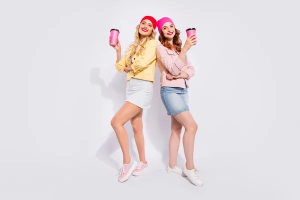 Pleine longueur photo de deux jolies dames avec boisson chaude à emporter dans les mains porter des vêtements décontractés isolé fond blanc — Photo