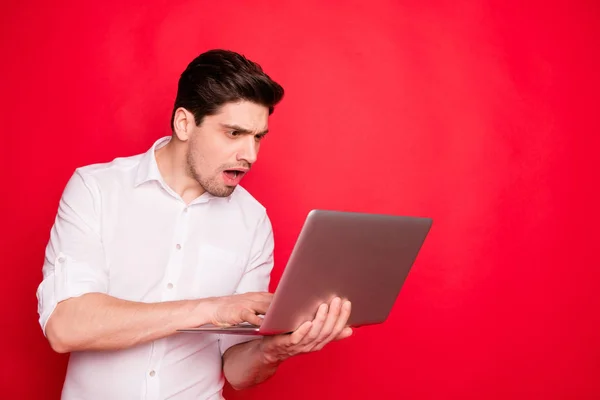 Foto di un uomo spaventato che indossa una camicia bianca senza vedere soldi sui suoi conti sullo schermo del computer portatile mentre isolato con sfondo rosso — Foto Stock