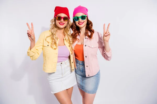 Foto de dos bellas damas que muestran símbolos de signo v usan gafas de sol ropa casual aislado fondo blanco —  Fotos de Stock
