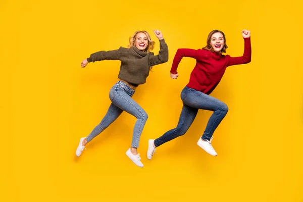 높은 서둘러 쇼핑 웨어 니트 스웨터 고립 된 노란색 배경을 점프 두 여성의 전신 사진 — 스톡 사진