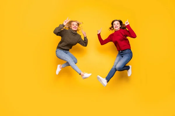 Foto de comprimento total de senhoras bonitos saltando alto mostrando v-sinais desgaste pulôveres de malha isolado fundo amarelo — Fotografia de Stock