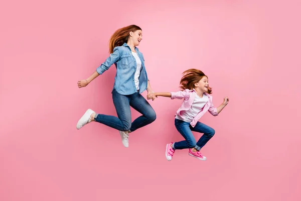 Foxy kleine Dame und ihre Mutter springen hoch rauschenden Spielzeugladen tragen lässige Jeans Outfit isoliert rosa Hintergrund — Stockfoto