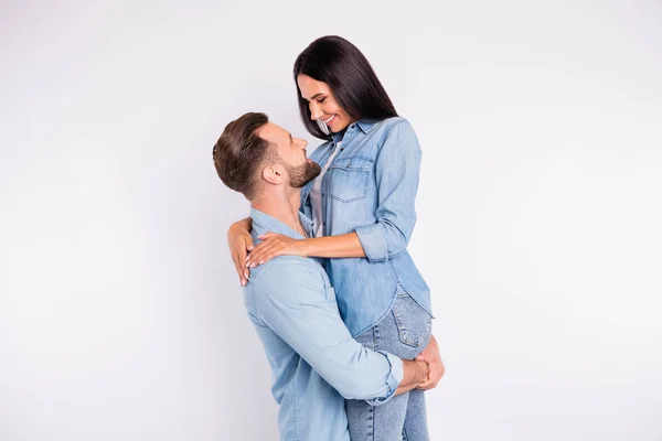 Profilbild von verträumten Ehepartnern, die lächelnd in Jeans-Hemd vor weißem Hintergrund kuscheln — Stockfoto