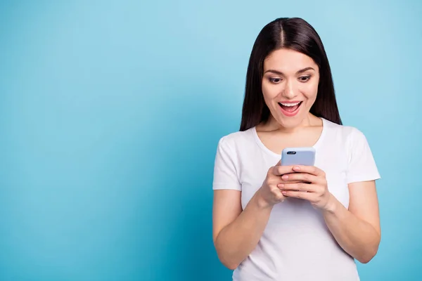 Фотография симпатичной симпатичной веселой девушки, которая видит информацию о продажах на своем телефоне, находясь в изоляции на синем фоне — стоковое фото