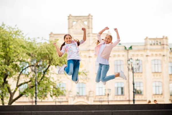 Comprimento total tamanho do corpo vista de dois agradável atraente alegre alegre descuidado pré-adolescente meninas vestindo casual se divertindo viajando passar férias fim de semana vista vendo marco regozijo — Fotografia de Stock