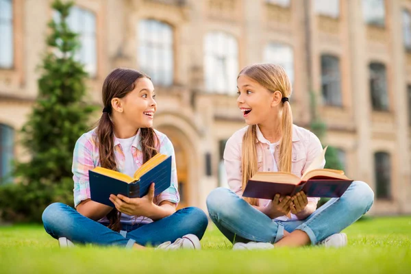 Portret van twee mooie aantrekkelijke schattig vrolijk vrolijke vrolijk blij brainy ijverig deskundig intelligent pre-tiener meisjes zittend op groene gras uitgaven dag weekend lezing buiten — Stockfoto