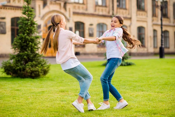 Dois agradável atraente adorável alegre alegre pré-adolescente meninas vestindo casual se divertindo viajando no exterior girando de mãos dadas passar férias tempo livre no ar fresco — Fotografia de Stock