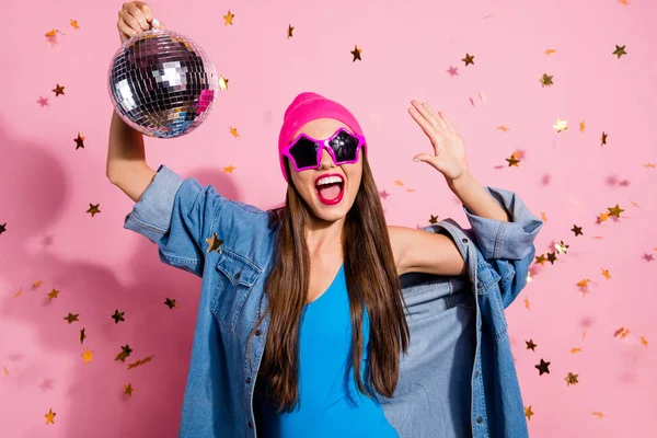 Крупним планом фото веселої жінки в окулярах окуляри, що тримає дзеркальний м'яч, показує свою долоню в блакитному костюмі тіла ізольовані на рожевому фоні — стокове фото