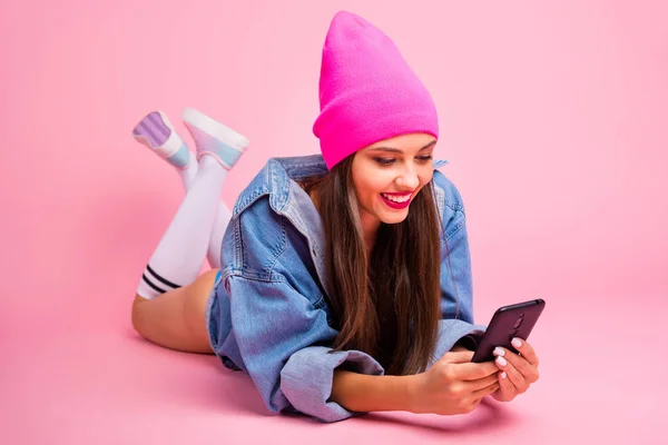 Portrait of lovelyl ady holding device reading information wearing denim jeans jacket socks isolated over pink background — Stock Photo, Image