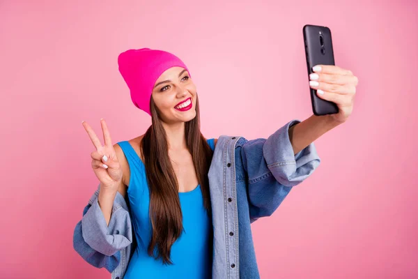 Портрет милої жінки, що робить фото v-знаки посміхається в синьому костюмі для тіла ізольовані на рожевому фоні — стокове фото