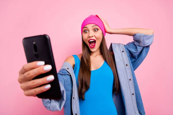 Portrait of astonished funny youth holding device screaming shouting touching her head wearing blue swim wear isolated over pink background — Stock Photo, Image