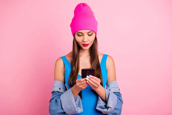 Portrait of concentrated woman holding device wearing blue bodysuit isolated over pink background — Stock Photo, Image