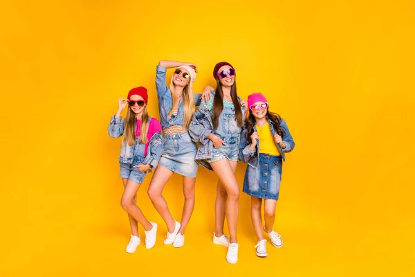 Фотографія повного розміру з чотирьох красивих досить барвистих захоплюючих фанатів вуличного стилю підлітків, які носять комбінезон в спідницях, обіймаючи ізольований яскравий фон — стокове фото