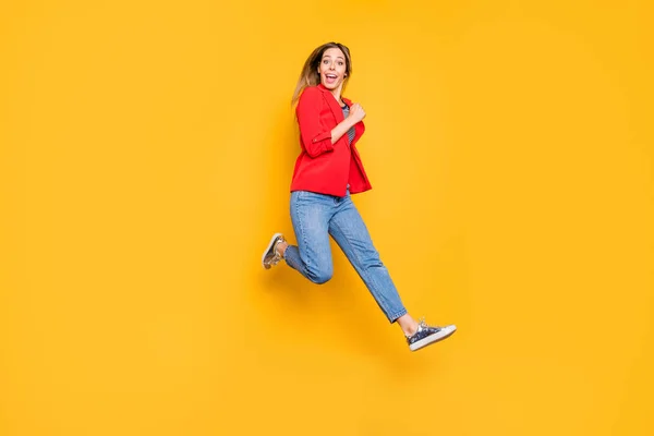 Foto de tamaño completo de linda chica saltando con camisa de rayas rojas chaqueta vaqueros aislados sobre fondo amarillo — Foto de Stock