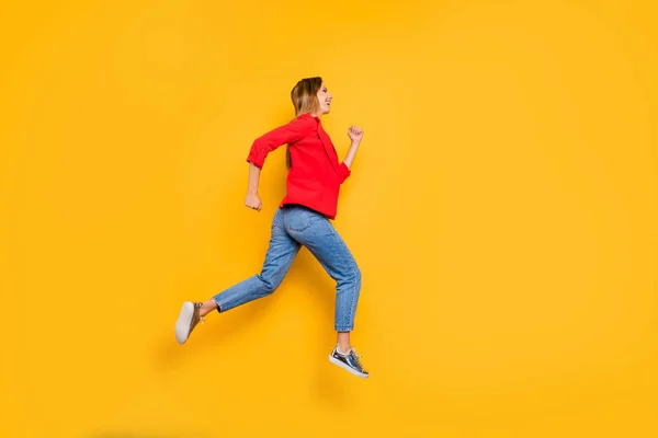 Foto lateral de perfil de cuerpo completo de la alegre dama corriendo usando pantalones vaqueros de chaqueta de camisa de rayas rojas aislados sobre fondo amarillo — Foto de Stock