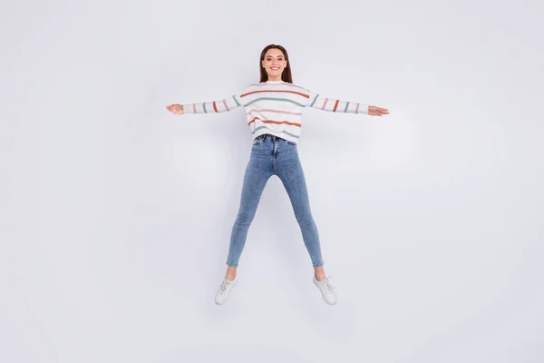 Foto de tamaño completo de la persona encantadora levantando las manos haciendo salto estrella con pantalones vaqueros de jersey a rayas aislados sobre fondo blanco — Foto de Stock