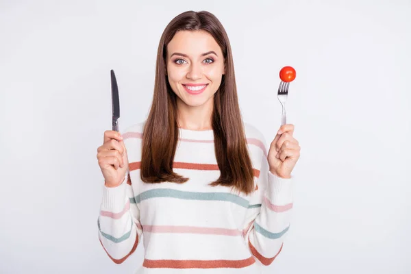 Portret van charmante vrouw houden tomaat kijken naar camera met toothy glimlach dragen gestreepte jumper geïsoleerd over witte achtergrond — Stockfoto