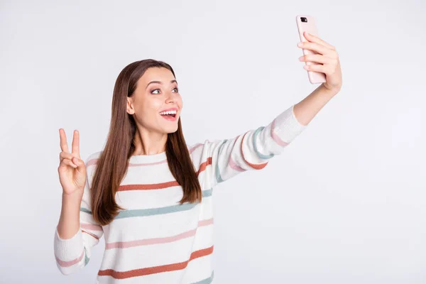 Красива дама робить селфі на новому телефоні, що показує символ v-знака, носити смугастий пуловер ізольований білий фон — стокове фото