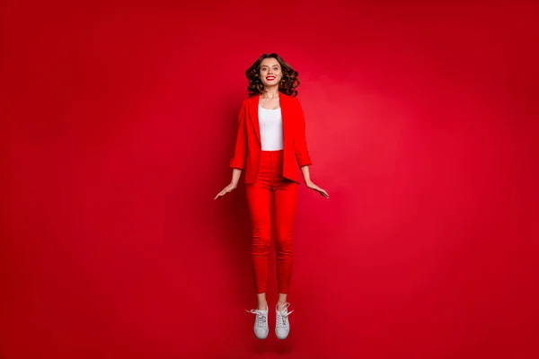 Фотографія повної довжини милої дівчини, що стрибає виглядає ізольовано на червоному тлі — стокове фото