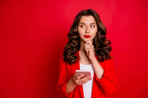 Portret van aantrekkelijk meisje met heldere lippen-stick touch haar kin denken met behulp van haar Smartphone geïsoleerd over rode achtergrond — Stockfoto