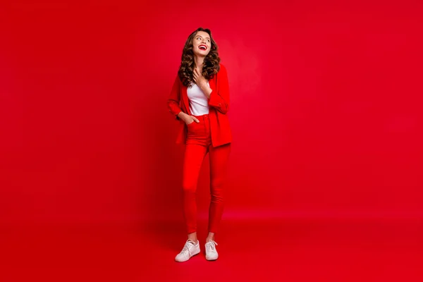 Full längd foto av charmig kvinna röra vid hennes bröst skratta klädd modern kostym isolerad över röd bakgrund — Stockfoto