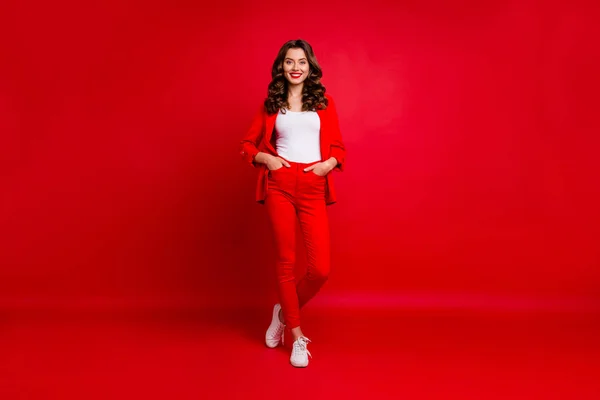 Foto em tamanho completo de senhora deslumbrante com as mãos colocadas em bolsos isolados sobre fundo vermelho — Fotografia de Stock