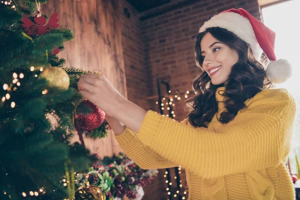 Alacsony alatt szög megtekintéséhez közelről fotó bájos lenyűgöző gyönyörű lány díszítő lány karácsonyfa viselése mellett sárga pulóvert és a Red Hat — Stock Fotó