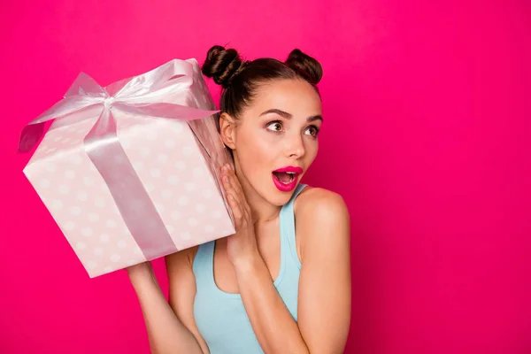 Wanita cantik memegang tangan giftbox besar menebak apa yang ada di dalamnya memakai pakaian santai terisolasi latar belakang merah muda — Stok Foto