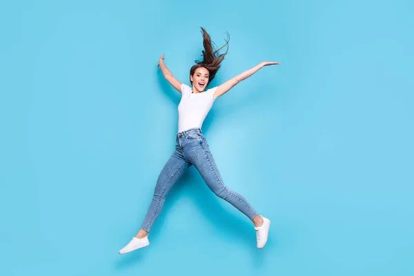 Foto em tamanho real de adolescente levantando as mãos gritando rindo vestindo branco camiseta jeans tênis isolados sobre fundo azul — Fotografia de Stock