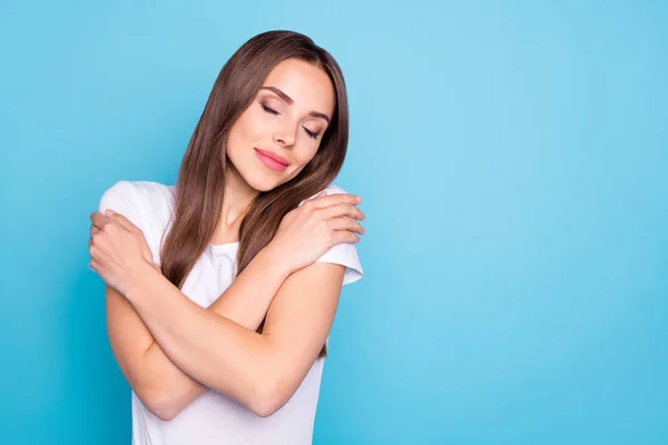 Retrato de senhora bonito tocando seus ombros fechando os olhos vestindo t-shirt branca isolada sobre fundo azul — Fotografia de Stock