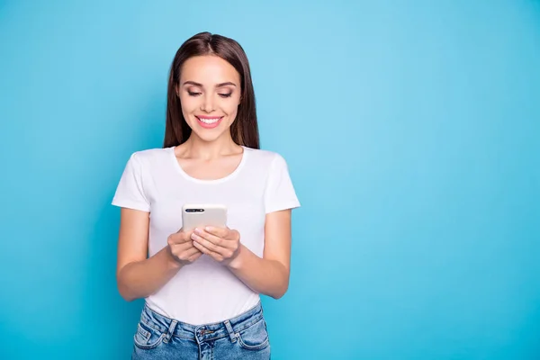Портрет очаровательной молодежи, смотрящей на чтение современных технологий в белой футболке на синем фоне — стоковое фото