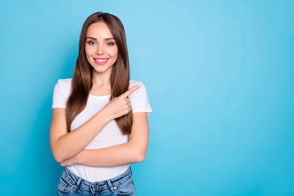 Retrato de pessoa encantadora apontando para o espaço de cópia mostrando anúncios vestindo jeans camiseta branca isolado sobre fundo azul — Fotografia de Stock