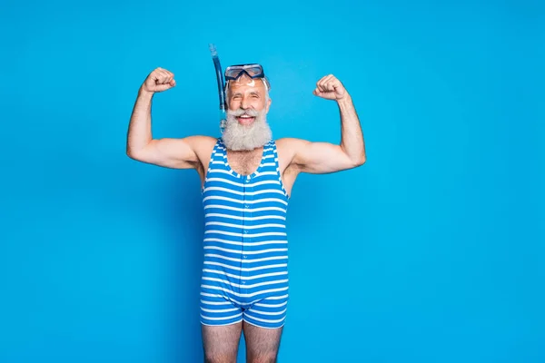 Retrato de jubilado jubilado alegre marinero con sus músculos riéndose usando ropa de baño a rayas aislado sobre fondo azul — Foto de Stock
