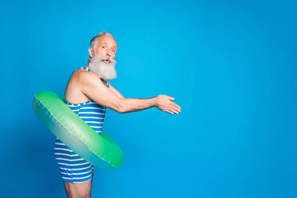 Foto del lado del perfil del anciano impresionado saltando con círculo redondo de goma usando ropa de baño a rayas aislada sobre fondo azul — Foto de Stock