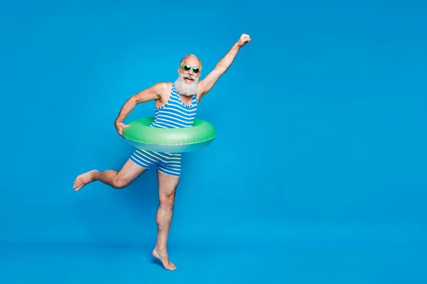 兴奋退休退休退休退休人士的全长照片，白发抬起拳头，头戴条纹泳装眼镜，在蓝色背景上隔离 — 图库照片