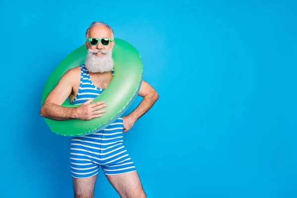 Ritratto di nonno allegro con occhiali da vista che tiene la cintura sulla spalla indossando abiti da bagno a strisce isolato su sfondo blu — Foto Stock