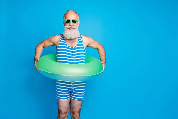 Retrato del hombre alegre con anteojos gafas que sostienen el cinturón de vida del anillo de goma usando ropa de baño aislada sobre fondo azul — Foto de Stock