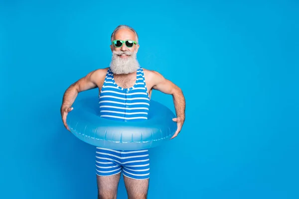 Ritratto di uomo affascinante con occhiali da vista in possesso di giocattolo anello rotondo cercando indossare usura nuoto isolato su sfondo blu — Foto Stock