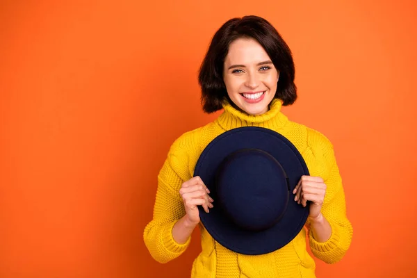 Foto av charmig glad söt trevlig tjej håller mössa med händerna medan isolerade med orange bakgrund — Stockfoto