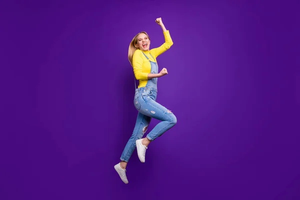 Full body foto di allegro teen alzando pugni urlando sì indossando giallo dolcevita jeans tuta isolata su sfondo viola viola — Foto Stock