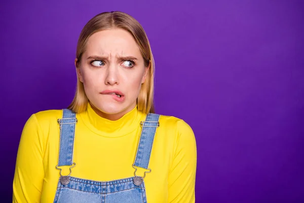Retrato de senhora frustrada olhando mordendo lábios vestindo gola amarela jeans jeans jeans macacão isolado sobre fundo amarelo — Fotografia de Stock