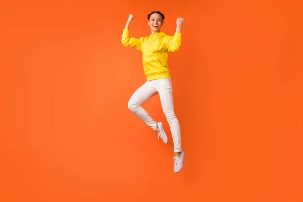 Foto de larga duración de persona alegre levantando puños gritando sí saltando aislado sobre fondo naranja — Foto de Stock